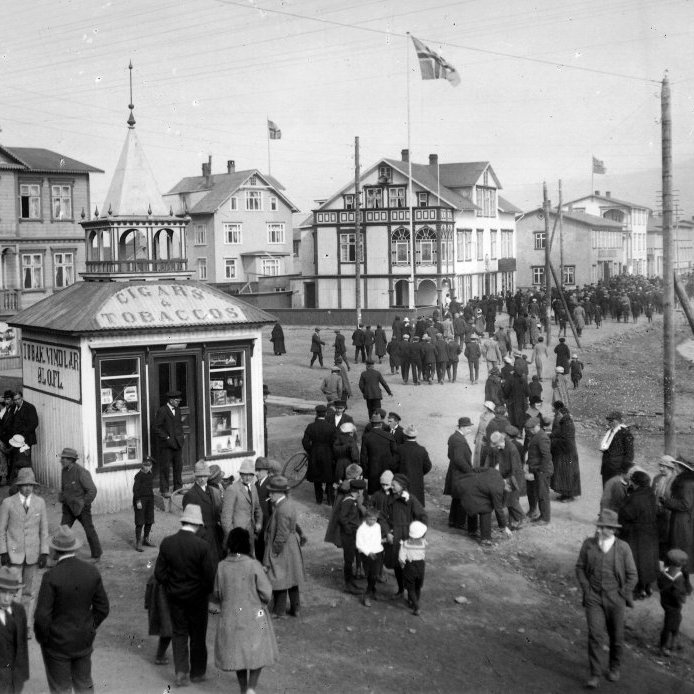 7. Sumardagurinn fyrsti í “Sóðavík” árið 1922. Víkin í Oddeyrarbótinni þar sem nú er Ráðhústorg var forðum kölluð Sóðavík því bæjarbúar óðu forina upp í ökkla og víkin þornaði ekki nema í allra mestu þurrkatíð. Lengi vel gekk sjórinn upp undir söluturninn sem Guðbjörn Björnsson byggði árið 1915 fyrir Jóhann Ragúelsson kaupmann. Turninn var síðar fluttur upp á hornið á Munkaþverárstræti og Hamarstígs. Ljósmynd Hallgímur Einarsson.