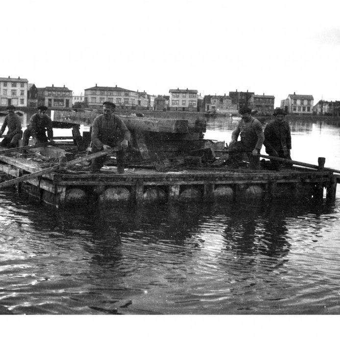 100. Bryggjusmiðir róa pramma við smíði norður hluta Torfunesbryggju, í miðbæ Akureyrar, árið 1927. Ljósmynd Egill Jónasson.
