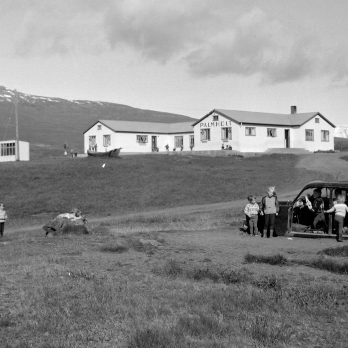 33. Barnaheimilið Pálmholt var tekið í notkun 1950. Þá var það staðsett töluvert fyrir ofan byggðina í kaupstaðnum. Það starfaði í þrjá mánuði yfir sumartímann og mánaðargjaldið var 200 kr. Álengdar sést í býlin, talin frá vinstri: Setberg, Skarð, Grafarholt og Bergland. Tvö seinni húsið eru nú horfin er Setberg og Skarð standa við Hamragerði í dag. Ljósmynd Gísli Ólafsson.