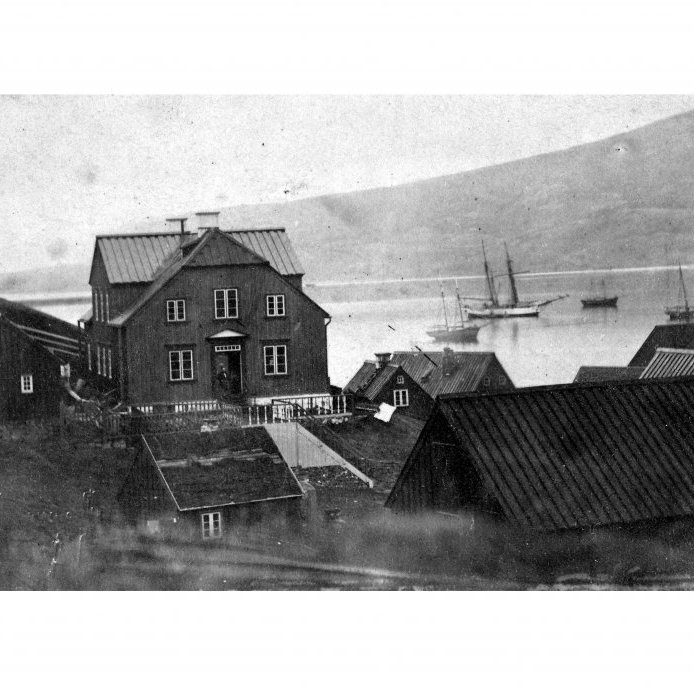 52. Akureyri um 1880. Reykur stígur upp frá skorsteinum. Oddur Thorarensen apótekari stendur í dyrum á Apótekinu, sem nú er Aðalstræti 4.
