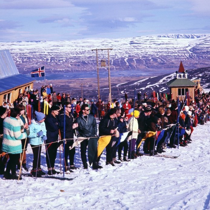 63. Skíðamót í Hlíðarfjalli árið 1967. Öll mannvirkin á þessari mynd eru nú horfin. Skíðalyftan er lengst til hægri. Turninn fyrir miðri mynd hét Strompurinn og var fyrsta mannvirkið sem reis upp á Stromp hæð. Húsið vinstra megin hét Strýta og er nýrisið en því var skipt út fyrir núverandi byggingu árið 2000. Ljósmynd Gunnlaugur P. Kristinsson.