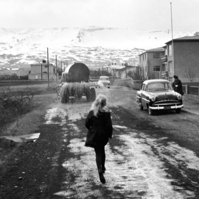 67. Pissubíllinn á leið upp Þingvallastræti. Ásdís Gunnlaugsdóttir hleypur á eftir bílnum um 1963. Ljósmynd Gunnlaugur P. Kristinsson.