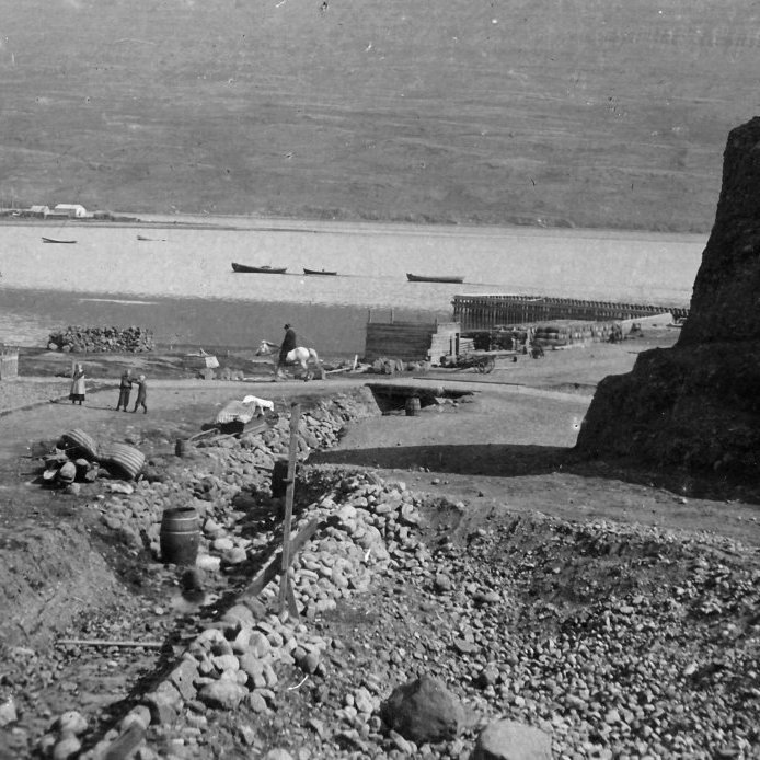 74. Torfunef í miðbæ Akureyrar um 1905. Þegar hér er komið við sögu hafði danskur timburmeistari O.W. Olsen hafist handa við að byggja nýja hafskipabryggju á Torfunefi . Bryggjan reyndist mikil hrákasmíði því daginn eftir að hún tekin í notkun hrundi hún og hluti af uppfyllingunni hennar með. Óárennilegur Eyrarlandshöfðinn sést til hægri. Efnið úr honum var notað í uppfyllngu við höfnina til ársins 1907. Ljósmynd Magnús Ólafsson.