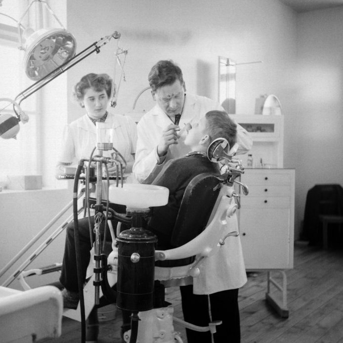 87. Tannlæknastofa í kjallara Barnaskóla Akureyrar. Kurt Sonnenfeldt gerir að tönnum skóladrengs um 1950. Ljósmynd Eðvarð Sigurgeirsson.