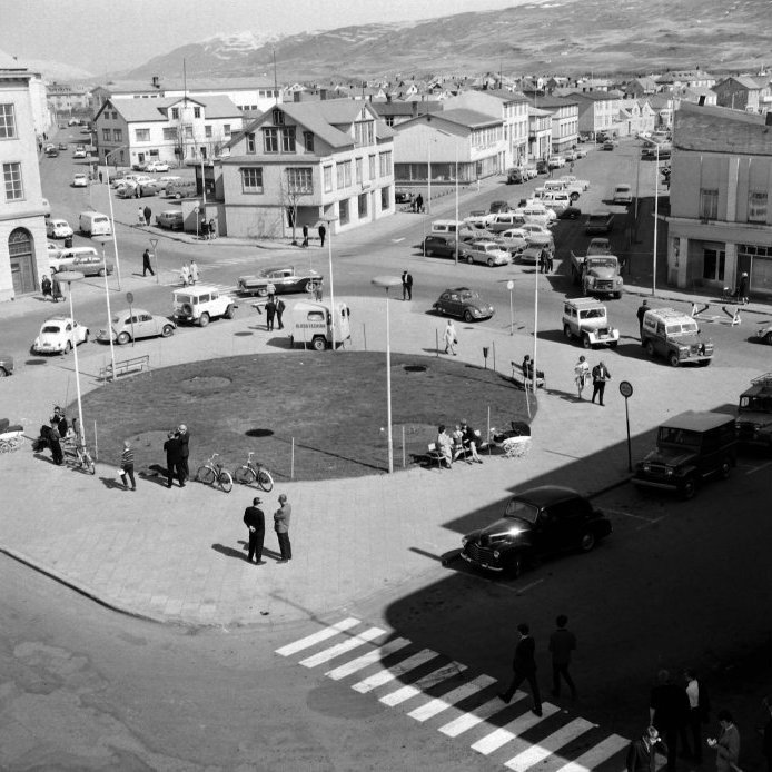 93. Ráðhústorg um 1967 með blaðavagninum hans Pálma. Útibú Búnaðarbankans stendur á horni Geislagötu og Strandgötu sem síðar var flutt út rétt út fyrir bæjarmörkin. Ljósmynd Sverrir Pálsson.