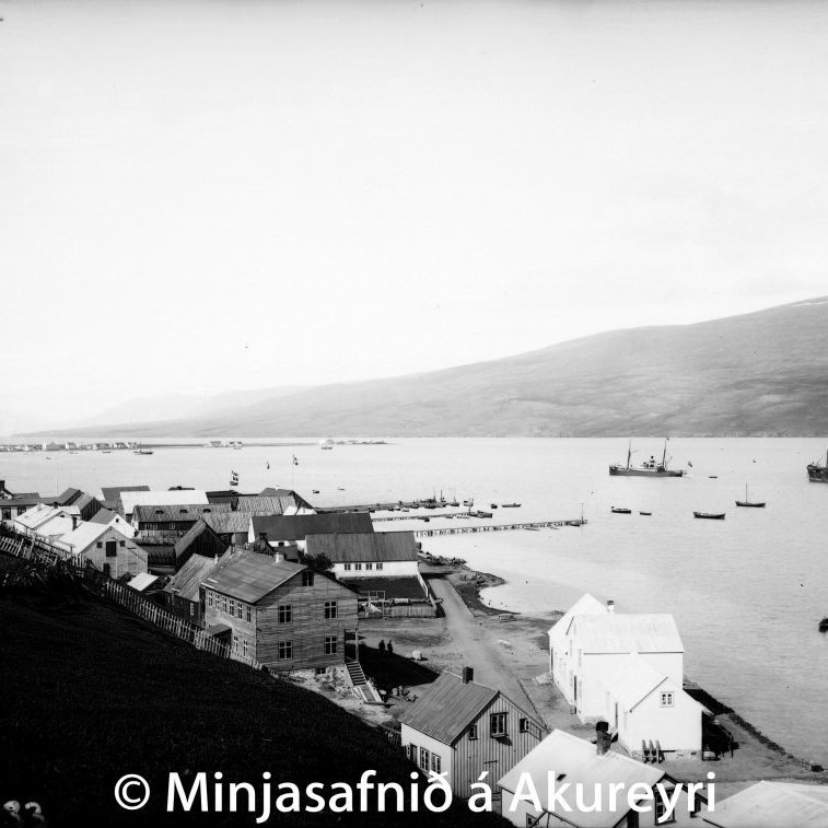 Akureyri árið 1900. Gatnamót Aðalstrætis og Hafnarstrætis. Aðalstræti 16 í smíðum. Nær sjónum er Hafnarstræti 2, verslunarhús Magnúsar og Friðriks Kristjánssona, byggt árið 1892, og Grundarskáli Magnúsar Sigurðssonar á Grund. Í húsi þeirra bræðra hóf útibú Landsbanka Íslands starfsemi sína árið 1902 og var þar til ársins 1904. Húsaþyrpingin á gömlu Akureyri og bryggjurnar framundan. Lengst til vinstri er Apótekið. en það hús stendur enn. Í fjarska sjást húsin á Oddeyri.