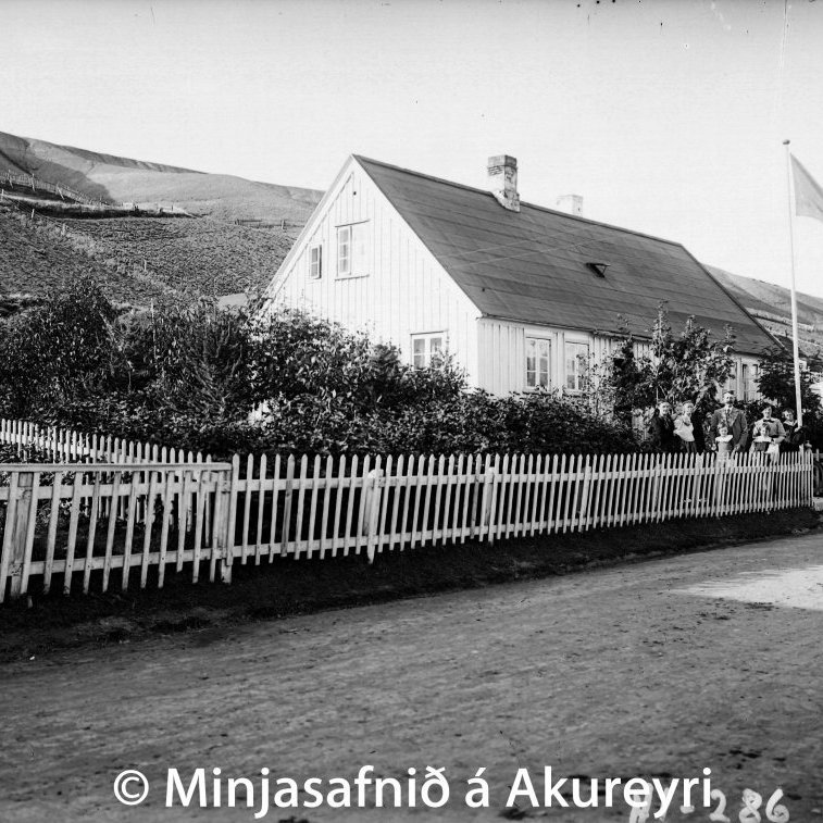 Jón Chr. Stephánsson, timburmeistari og bæjarfulltrúi (f. 1829 - d. 1910) og ljósmyndari er hér ásamt fjölskyldu sinni fyrir utan heimili sitt Aðalstræti 52, sem byggt var árið 1840. Dóttir hans, Svafa, var ein mikilvirkasta leikkona á Akureyri í áratugi. Á síðustu árum ævi sinnar tók Jón að sér alla tilsjón og gæslu trjágarðsins, sem var sunnan við kirkjuna og gerður var um aldamótin.
Aðalstræti 52 byggt 1840, Vilhelmína Lever bjó í húsinu og seldi veitingar 1853. Sveinn Skúlason keypti húsið af Vilhelmínu, svo eignaðist húsið Jón Chr. Stephánsson 1862 og bjó þar til 1910. Jón lærði smíðar erlendis og einnig ljósmyndagerð. Hann hafði smíðaverkstæði í norðurenda hússins, en ljósmyndastofu, hina fyrstu á Akureyri í áföstum skúr. Jón var mikill garðyrkjumaður og ræktaði trjágarð við hús sitt um 1890 og telja menn hann elstan slíkra garða á Akureyri.