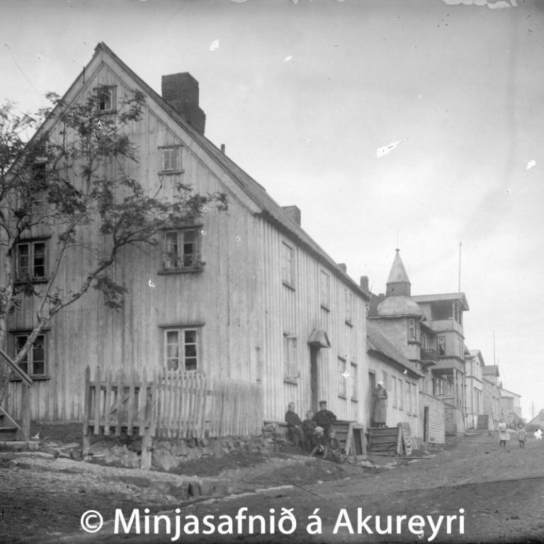 Gamli spítalinn, Gudmanns Minde“, Aðalstræti 14, sem Eggert Johnsen læknir reisti árið 1836. Friðrik Gudmann kaupmaður keypti húsið að áeggjan Bernhards Steincke og gaf bænum það til notkunar fyrir sjúka. Var spítalinn vígður við hátíðlega athöfn 7. Júlí 1874 í viðurvist landshöfðingja og annars stórmennis. Fjær er Hótel Akureyri, þá Berlín, verslunarhús Sigvalda og Jóhannesar Þorsteinssona, og á horni Aðalstrætis og Lækjargötu er hús séra Geirs Sæmundssonar.