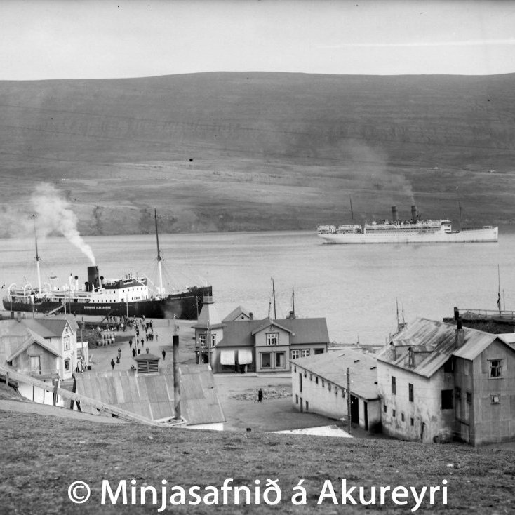 Akureyri um 1929. Skemmtiferðaskip á Pollinum. Dronning Alexandrine, skip Sameinaða gufuskipafélagsins danska, við Torfunefsbryggju. Gudmanns Efterfölger verslun fyrir miðju og gisti- og hesthúsið Caroline Rest til hægri.