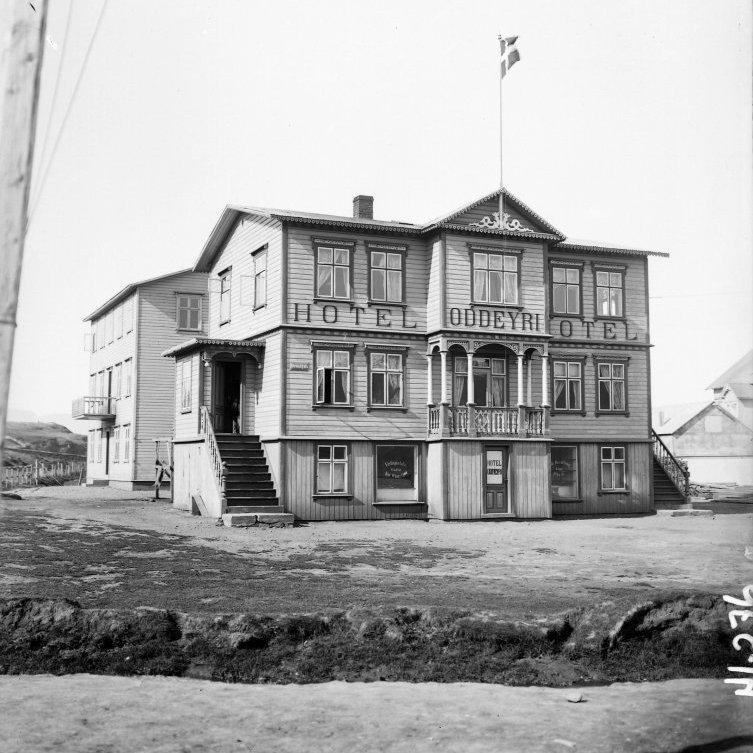 Hótel Oddeyri, Strandgata 1, sem Anton Jónsson reisti árið 1904. Hótelið var þar um langt árabil, en síðar skiptist húsið á fleiri eigendur. Árið 1924 eignaðist Jón Sigurðsson, ljósmyndari, efri hæðina og rak þar ljósmyndastofu í mörg ár. Hann var nemandi Hallgríms Einarssonar í iðninni. Hjá honum unnu Vigfús Friðriksson og Vigfús Sigurgeirsson, en þeir voru einnig nemendur Hallgríms. Síðar eignaðist Óskar Sæmundsson kaupmaður neðri hæðina og rakverslunina Esju á jarðhæð. Húsið var rifið árið 1949.  ̶  Á bakvið sér á Brekkugötu 2, hús Valdemars Thorarensen, sem byggt var árið 1904 og rifið 1962.