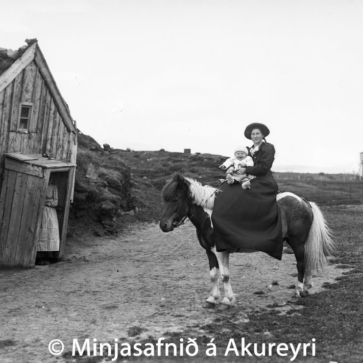 Á hlaðinu á Stóra-Eyrarlandi árið 1913. Kristín Guðmundsdóttir á Skjóna með dóttur sína, Snjólaugu Baldvinsdóttur. Anna Tómasdóttir, kona Jóns Helgasonar, sést í bæjardyrunum. Eyrarlandsbærinn var rifinn árið 1949.