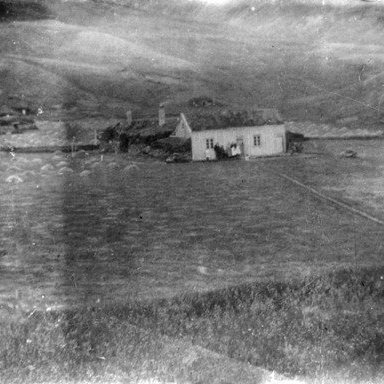 Reykir, Fnjóskadal, S-Þing. Tún í dríli, tv. er smiðja við bæjarlækinn. Norðan og vestan við hana er hesthúsið en yfir bæinn ber geitakofa og hænsnakofa.