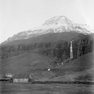 Búðareyri á Seyðisfirði. Strandartindur í baksýn og Búðarárfoss fyrir neðan. Ljósmyndin er líklega tekin á fyrstu áratugum síðustu aldar. Steingarðurinn sem sést á myndinni var horfinn um eða uppúr miðri öldinni.
Þökkum Sólveigu Sigurðardóttur frá Seyðisfirði fyrir upplýsingarnar.