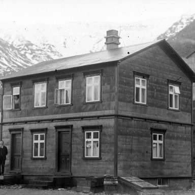 Hús Gríms Grímssonar skólastjóra á Ólafsfirði, hann við hús og Bjarnveig Helgadóttir í glugga.